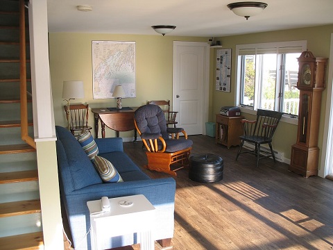 Living room with queen couch, closed bathroom door & ocean facing picture window